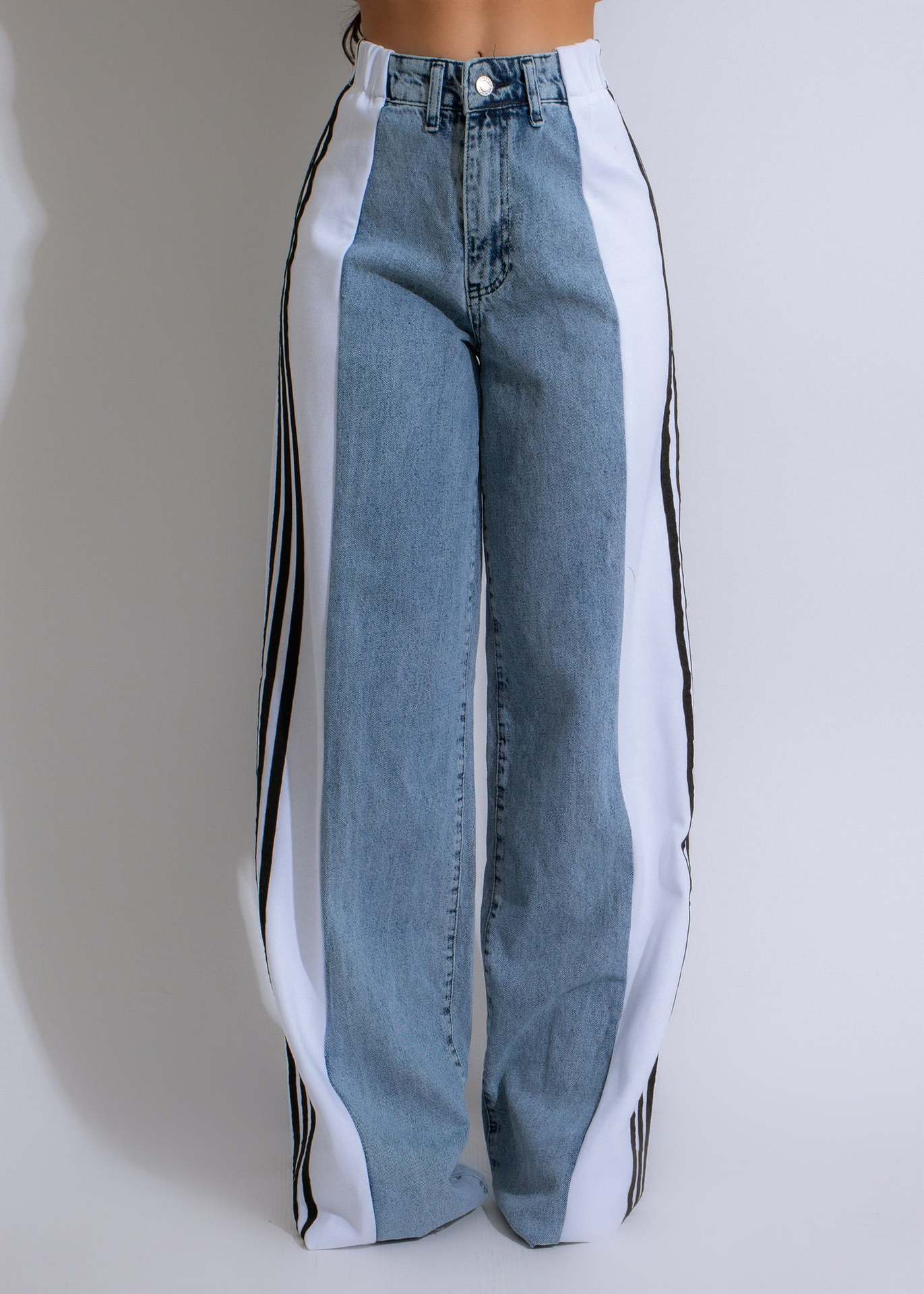 Blue jeans with white side panels on a plain background