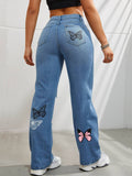 Back view of woman wearing high-waisted straight leg blue jeans with butterfly print on a plain background.