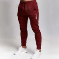 Men’s maroon jogger pants with brand logo on gray background – casual gym or streetwear