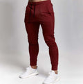 Maroon jogger pants worn by a person on a plain background