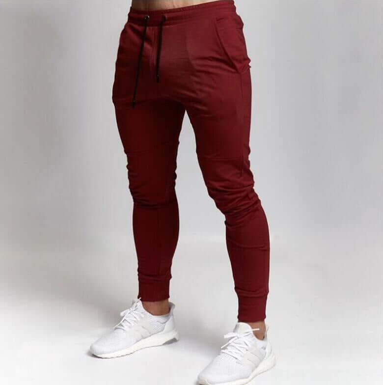 Maroon jogger pants worn by a person on a plain background