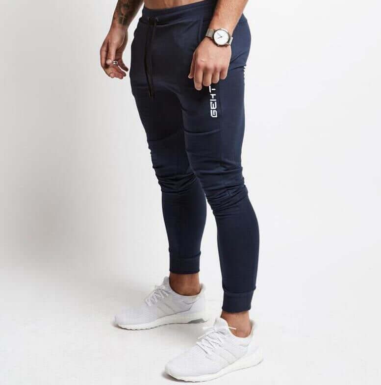 Person wearing navy jogger pants with a brand logo on a white background