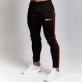 Black men’s gym jogger pants with red stripes and 'GENT' logo on white background