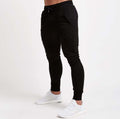 Black jogger pants worn by a person on a white background