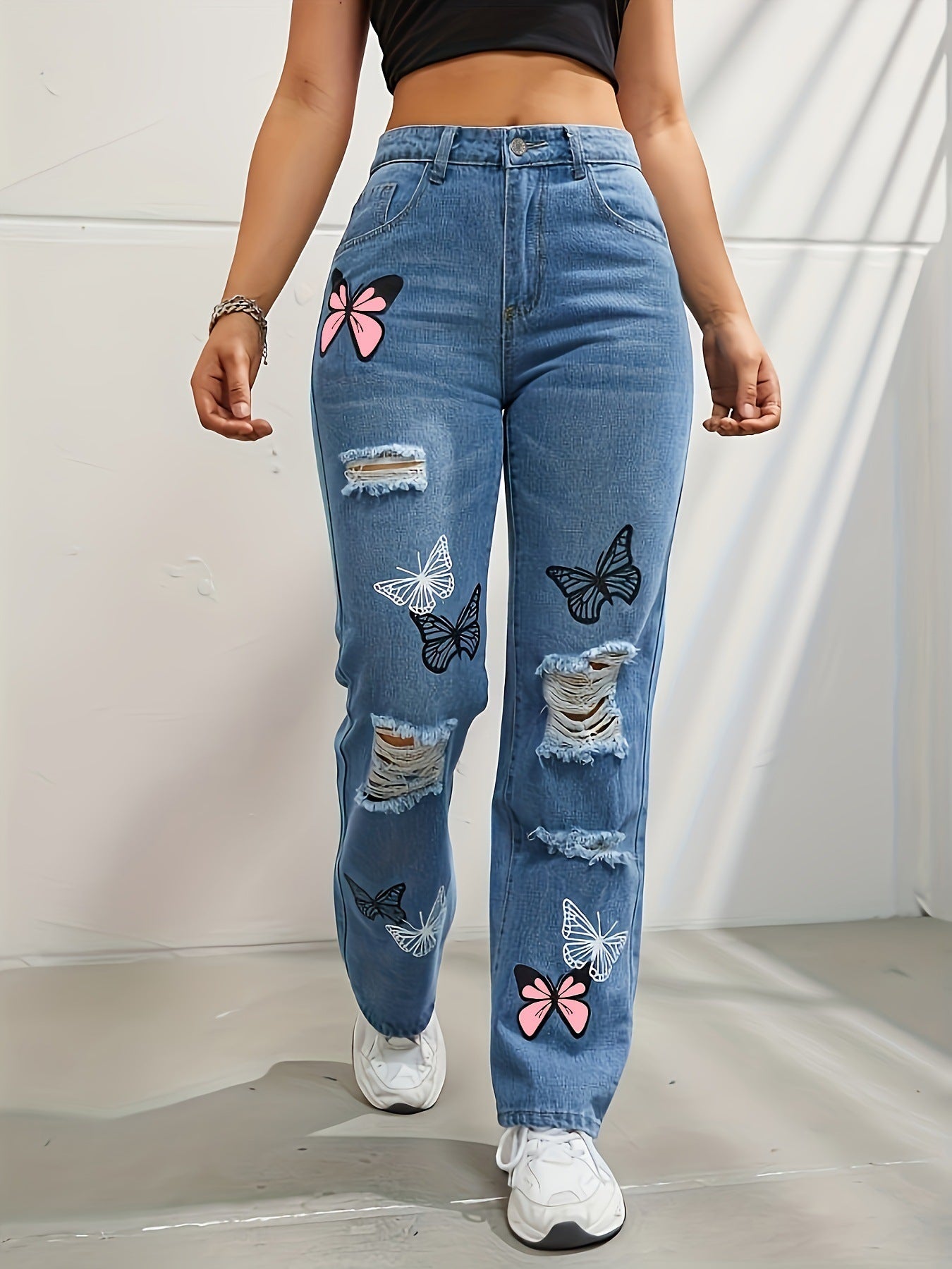 Person wearing blue jeans with butterfly patches on a plain background