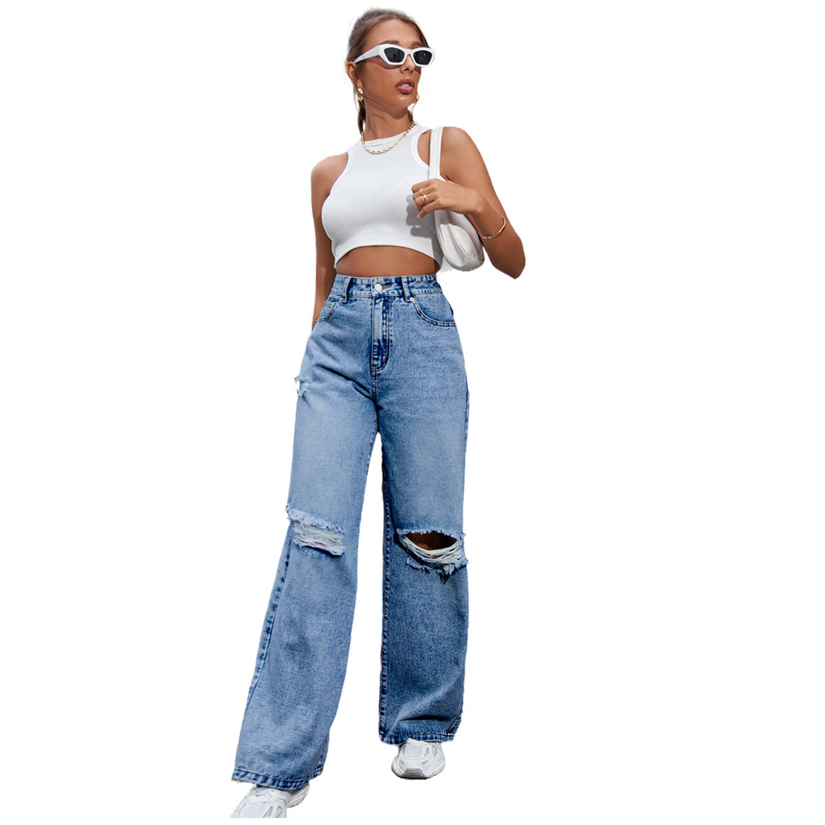 Woman wearing a white crop top and blue ripped jeans on a white background