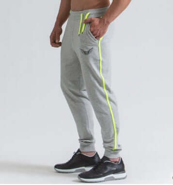 Person wearing gray jogger pants with neon green accents on a light gray background