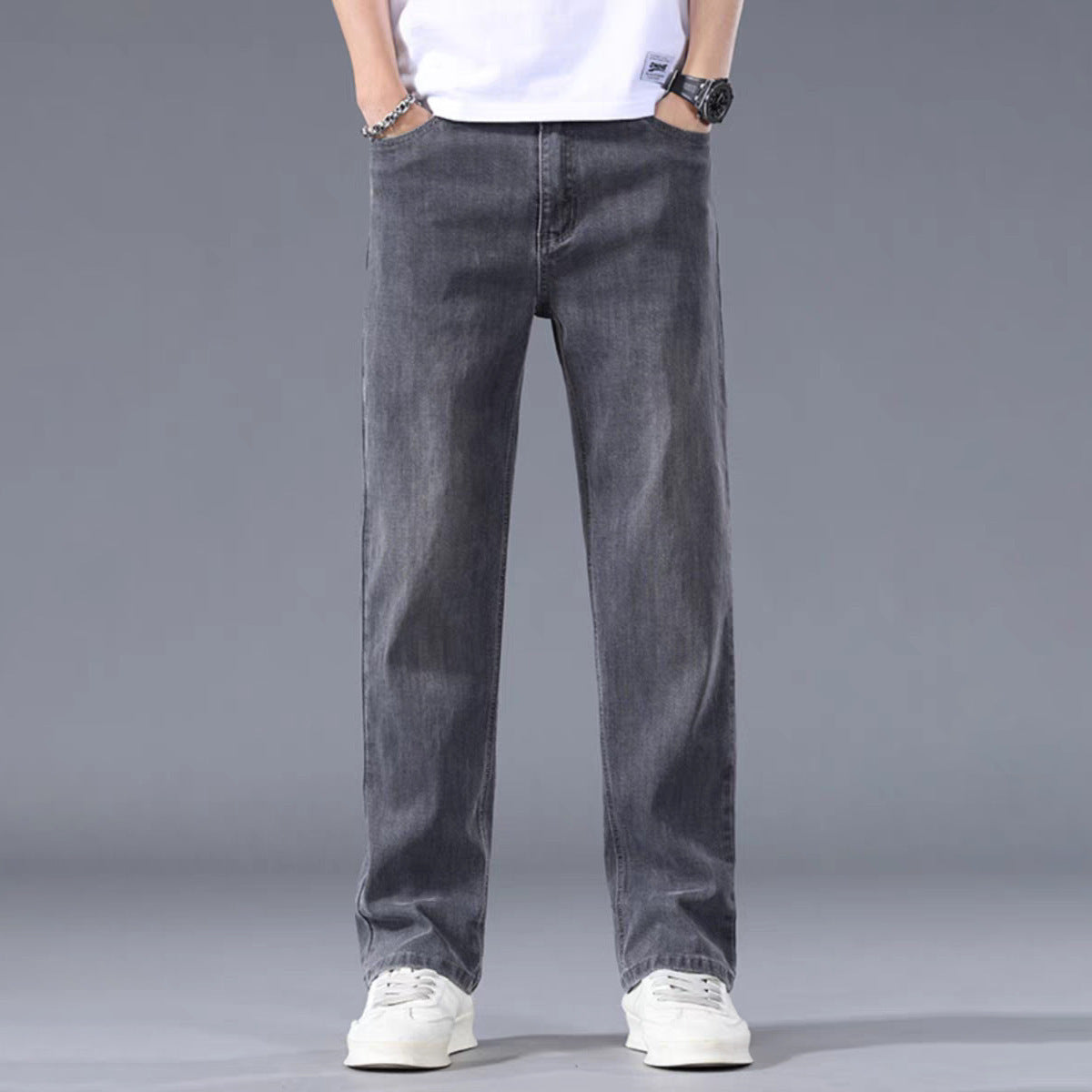 Person wearing gray jeans and a white shirt on a gray background