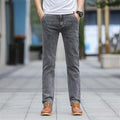 Person wearing gray jeans and brown shoes on a blurred outdoor background