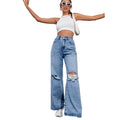 Person wearing a white crop top and ripped blue jeans on a white background