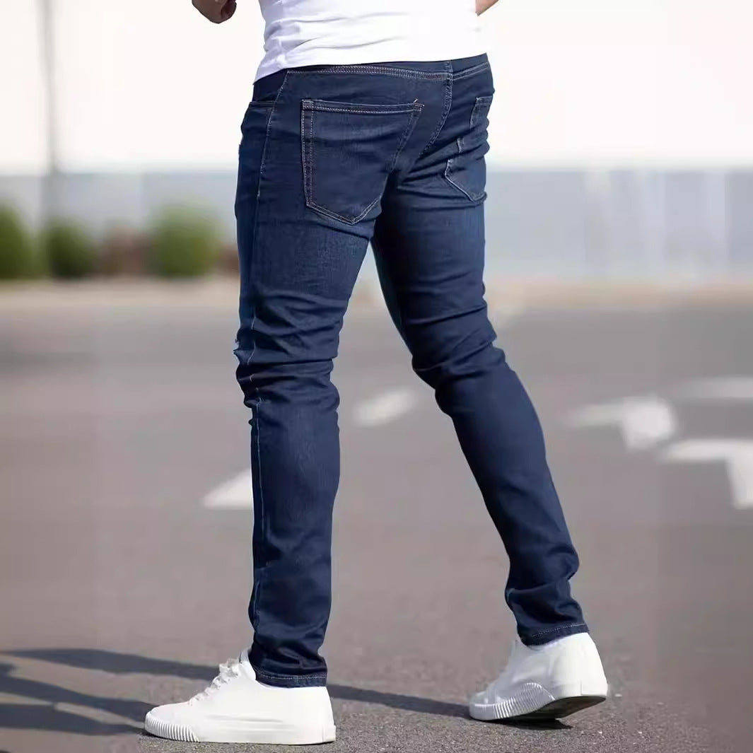 Person wearing blue jeans and white sneakers on a blurred street background