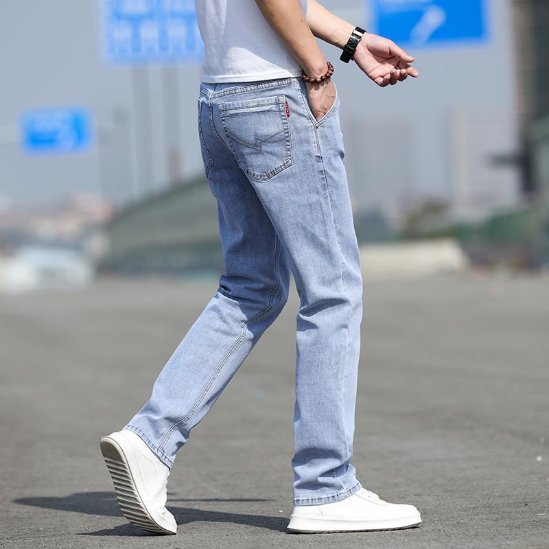 Person wearing light blue jeans and white sneakers on a blurred background