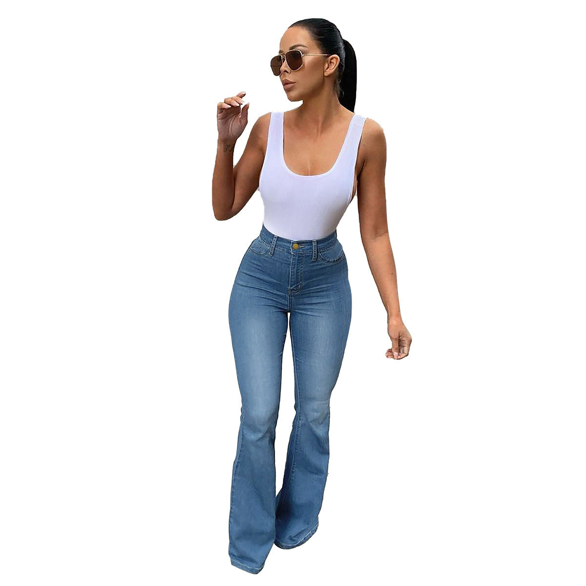 Woman wearing blue high waist stretch bootcut jeans and a white tank top on a white background.