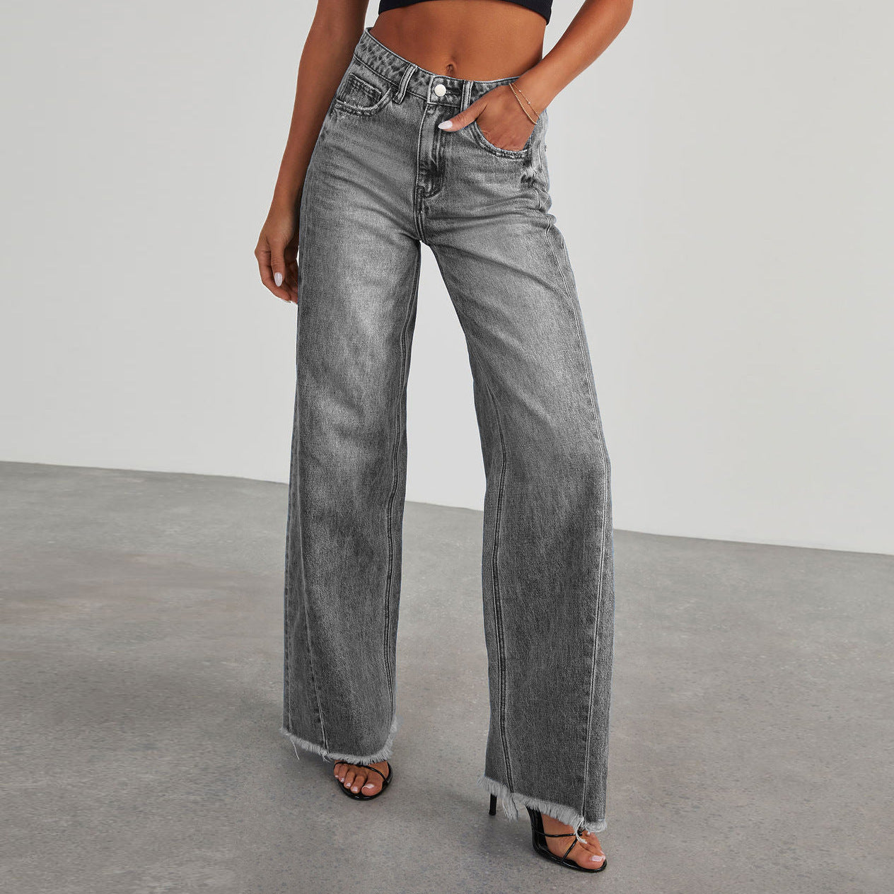 Person wearing gray wide leg jeans with a straight leg design on a plain background.