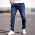Person wearing blue jeans and white sneakers on a blurred street background