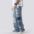 Person wearing patchwork jeans on a plain background