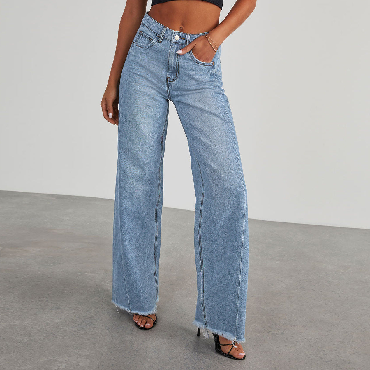 Person wearing light blue wide leg jeans with a straight leg design on a plain background.