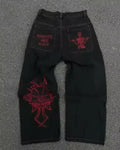 Black jeans with red embroidery on a gray surface