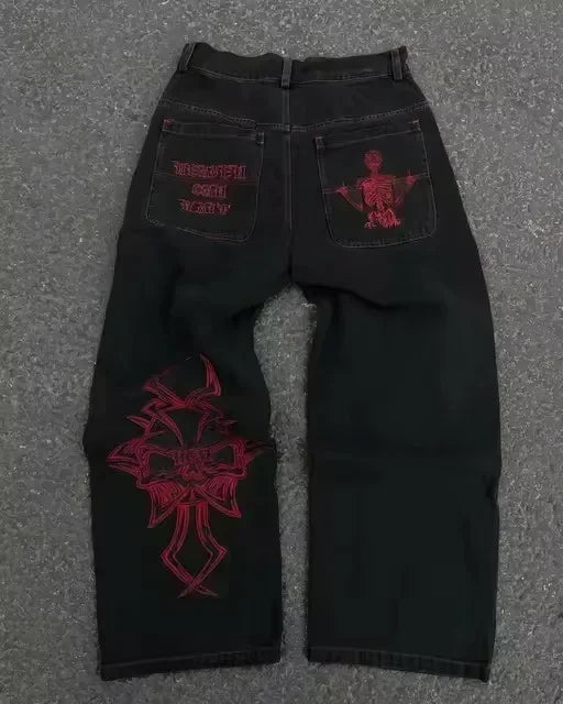 Black jeans with red embroidery on a gray surface