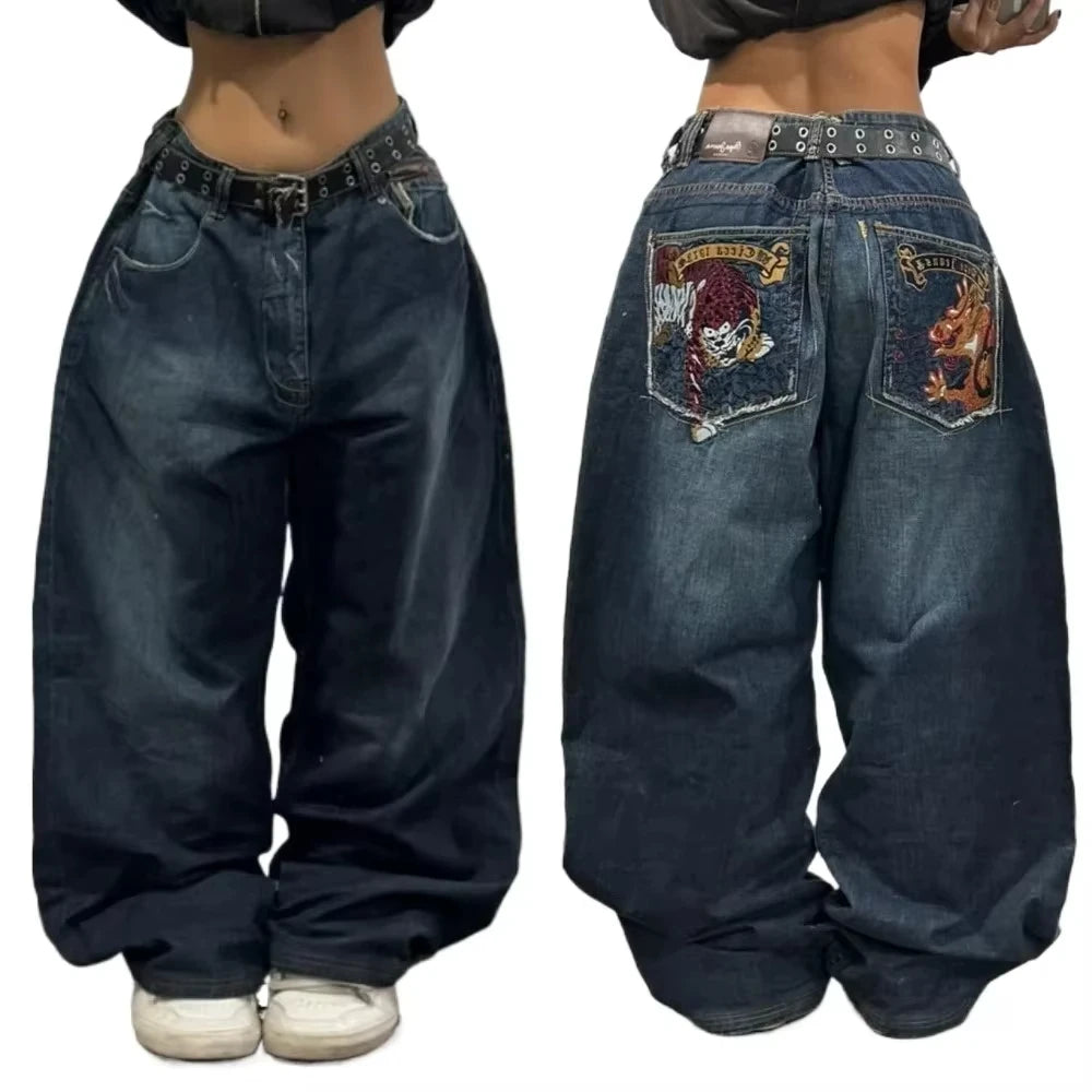 Blue jeans with embroidered designs on the back pocket worn by a person.
