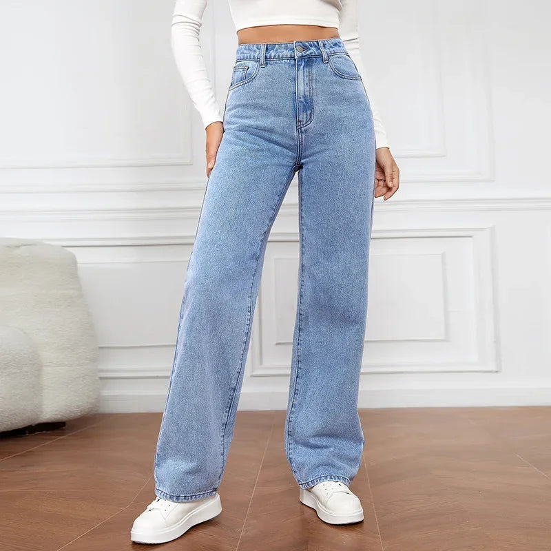 Woman wearing high-waisted retro baggy light blue jeans standing on a white background