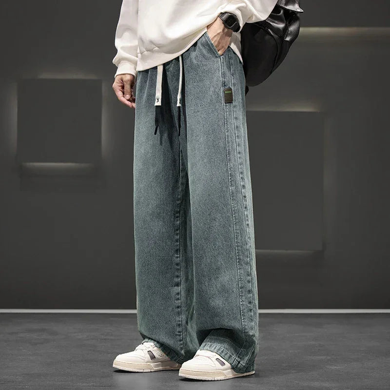 Person wearing wide-leg jeans and a white sweatshirt in a minimalistic setting
