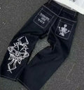 Black jeans with white embroidered designs on a textured surface