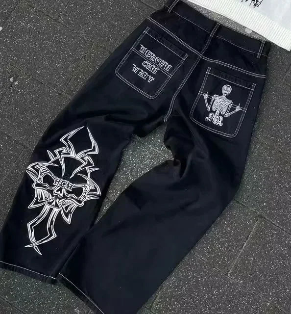 Black jeans with white embroidered designs on a textured surface