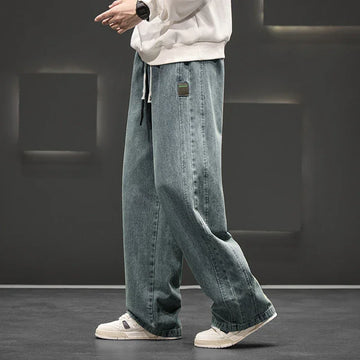 Men wearing light blue wide-leg loose straight fit denim jeans with a white sweatshirt on a dark background