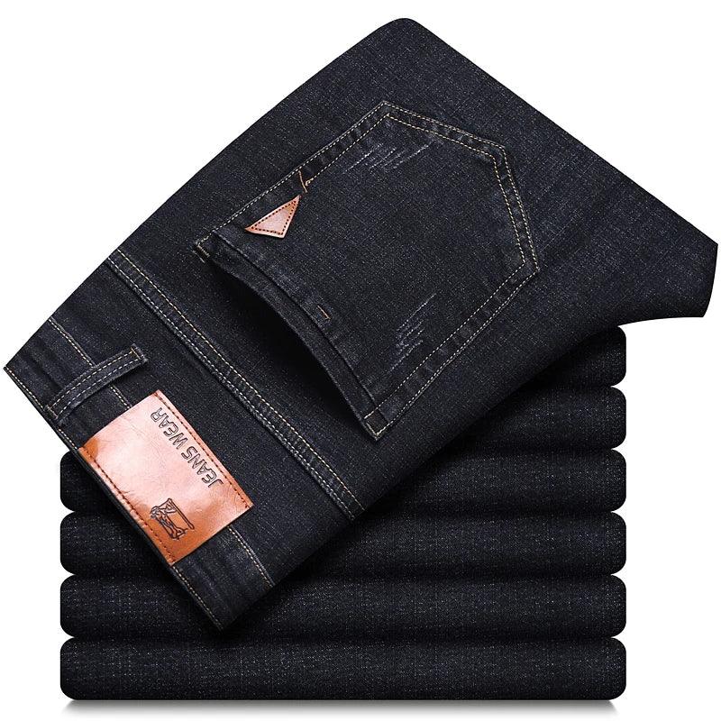 Stack of dark blue jeans with a brand label on a white background