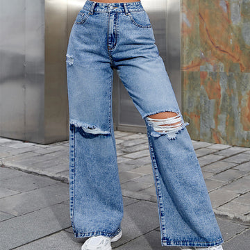 Ripped blue jeans worn by a person on a city street.