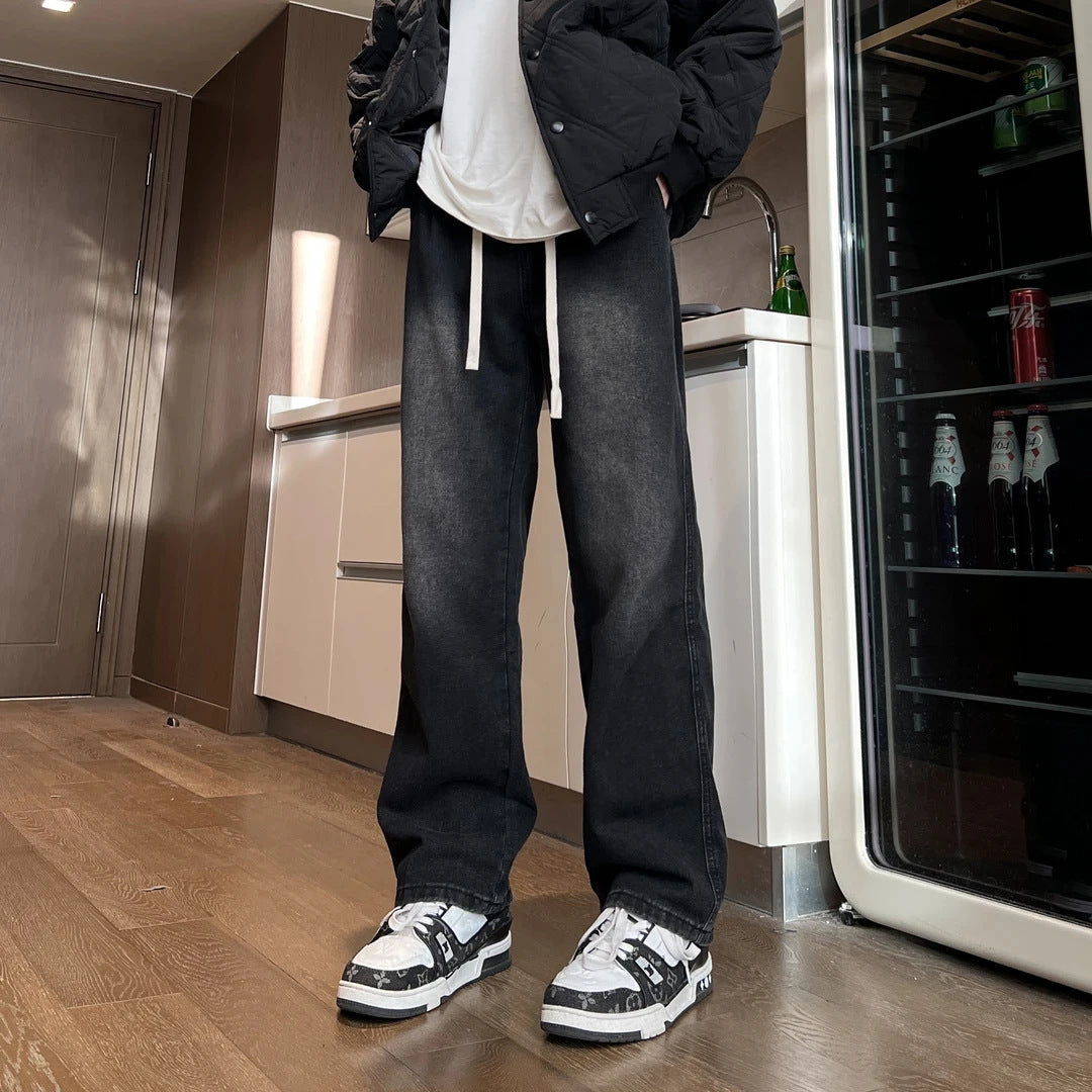 Man wearing black jeans and sneakers in a modern kitchen.
