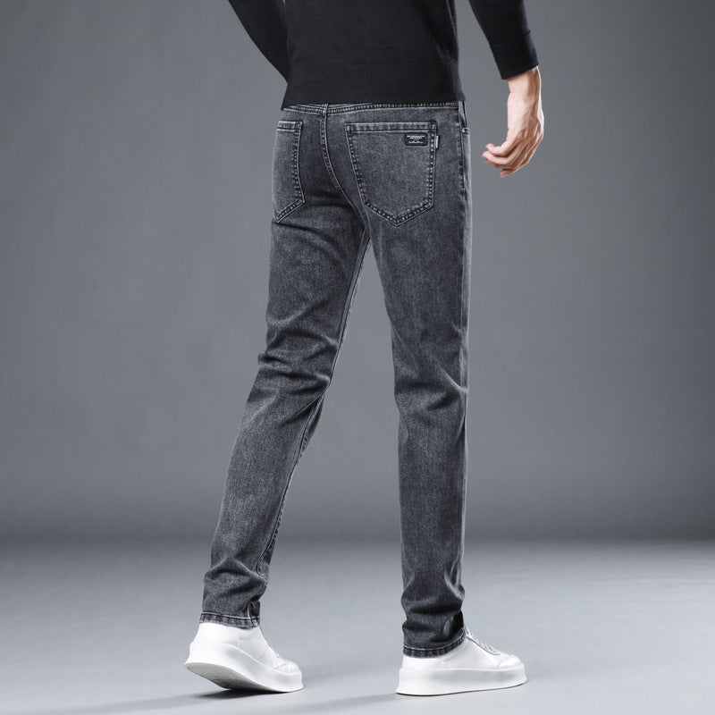 Person wearing gray jeans and white shoes on a gray background
