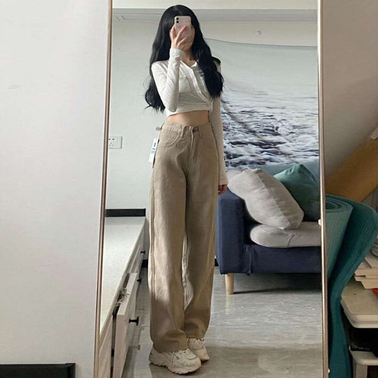 Woman wearing high waist wide-leg beige jeans with a white crop top taking a mirror selfie in a room