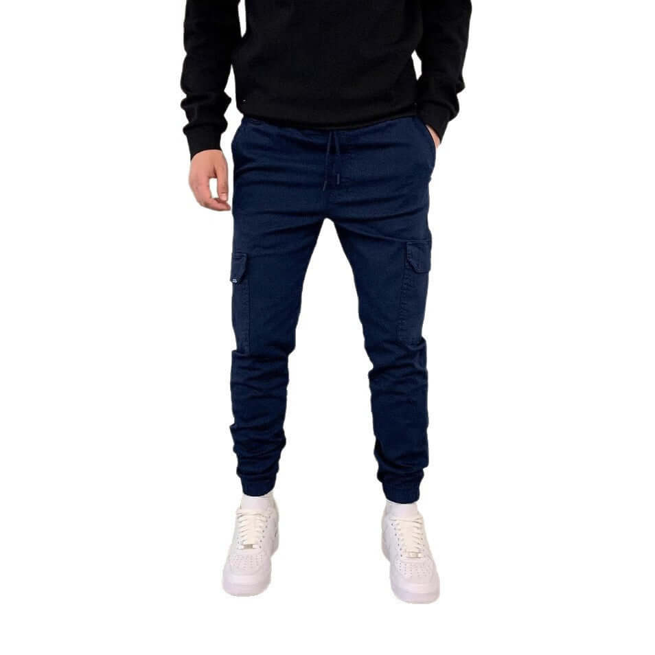Man wearing navy cargo jogger pants with a black top on a white background