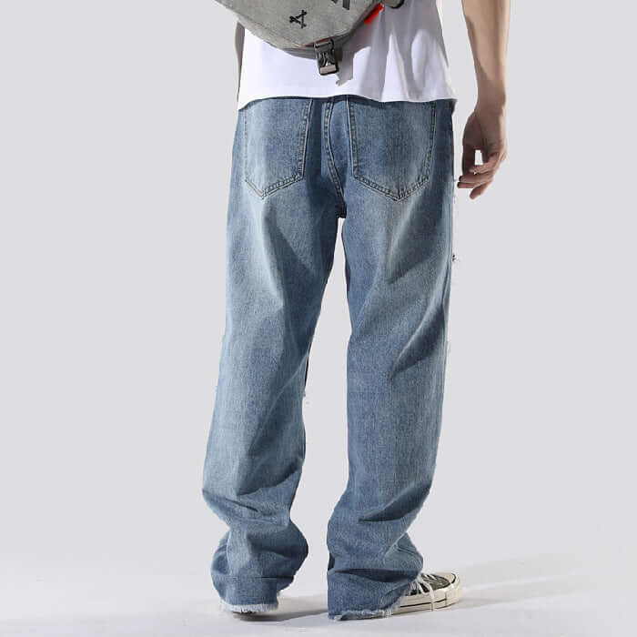 Person wearing blue jeans and a white shirt on a plain background