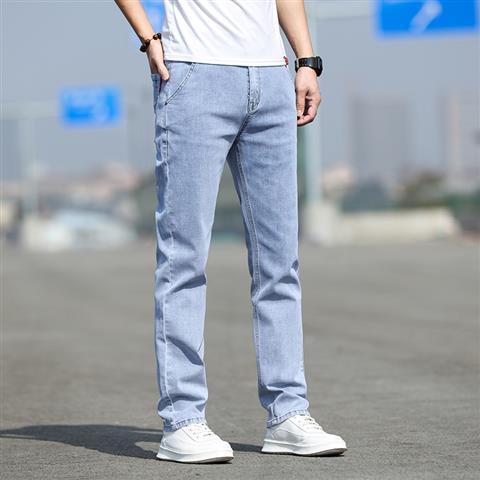 Person wearing light blue jeans and white sneakers on a blurred street background